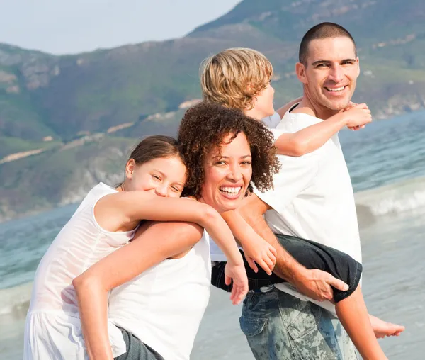 Parents giving two young children piggyback rides — Stock Photo, Image