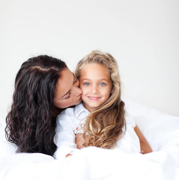Mladá matka a daugther všeobjímající na posteli — Stock fotografie