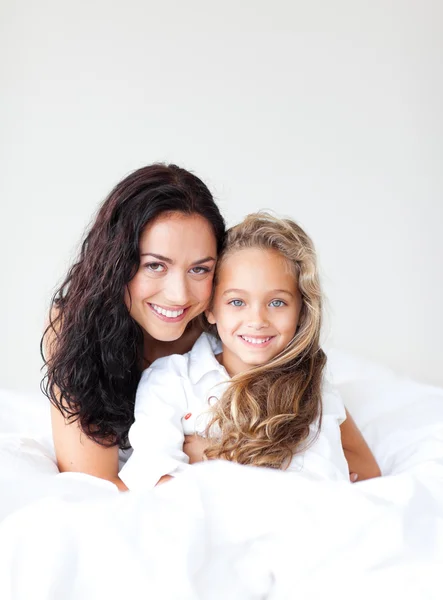Ung mamma och dotter embracing på sängen — Stockfoto