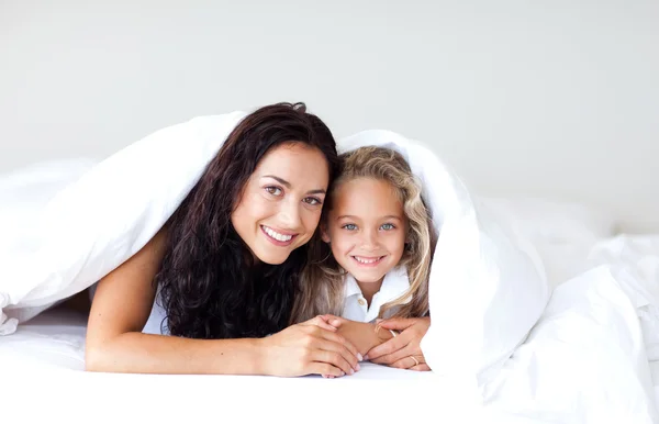 Charmiga mor och dotter embracing på sängen — Stockfoto