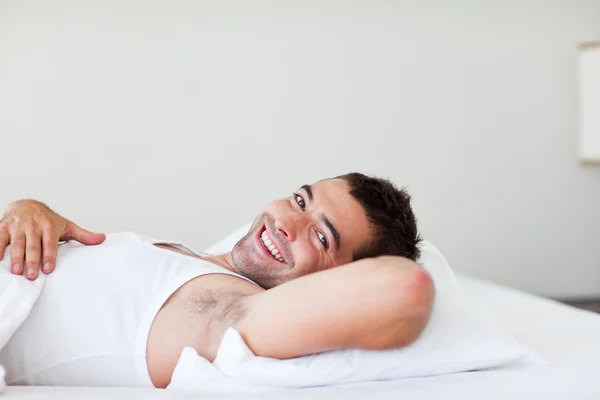 웃 고 있는 침대에 누워 하는 잘생긴 남자 — 스톡 사진