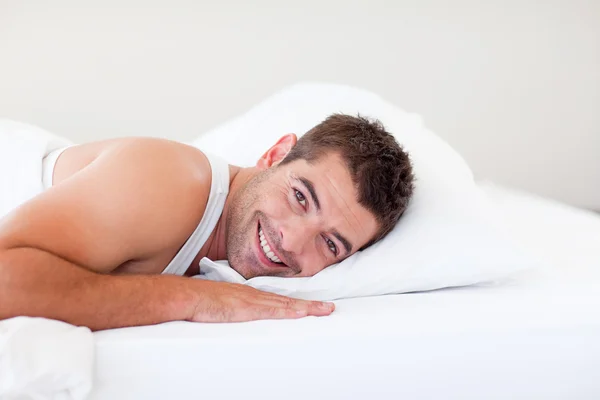 Hombre guapo acostado en la cama sonriendo — Foto de Stock