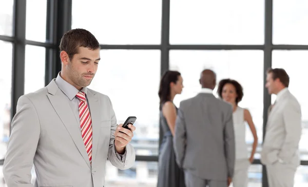 Joven hombre de negocios al teléfono en la oficina con su equipo — Foto de Stock