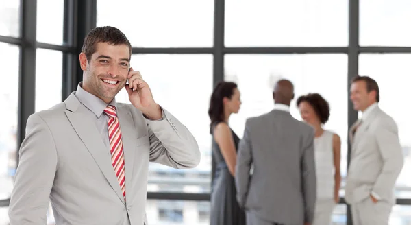 Young businessman on phone in office with his team — Stock Photo, Image