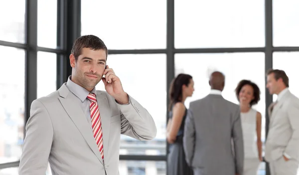 Young businessman on phone in office with his team — Stock Photo, Image