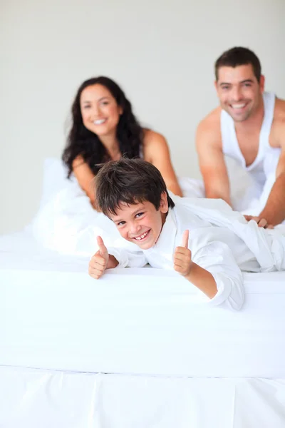Hijo con los pulgares arriba jugando en la cama — Foto de Stock
