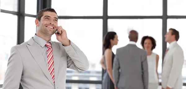 Schöner Geschäftsmann telefoniert im Büro mit seinem Team — Stockfoto