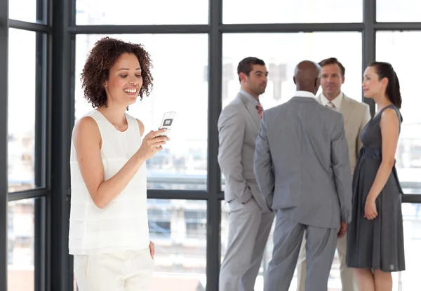 Glimlachende zakenvrouw op telefoon in kantoor met haar team — Stockfoto