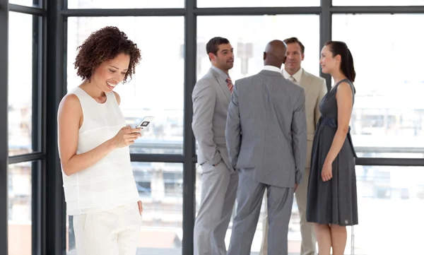 Glimlachende zakenvrouw op telefoon in kantoor met haar team — Stockfoto