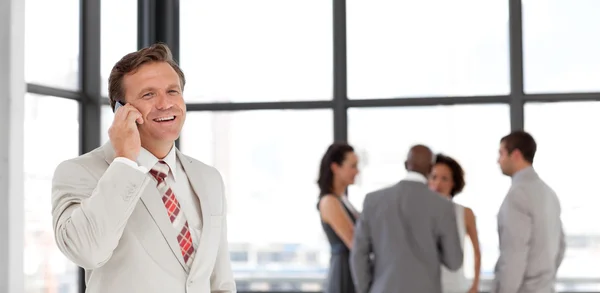 Portret uśmiechający się biznesmen na telefon z zespołem — Zdjęcie stockowe