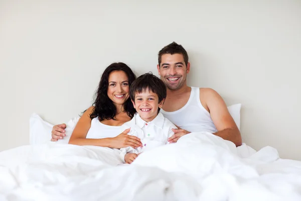 夫妇和儿子一起躺在床上在对照相机微笑 — 图库照片