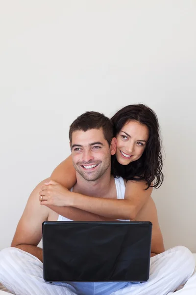 Mooie paar met behulp van een laptop op een bed — Stockfoto