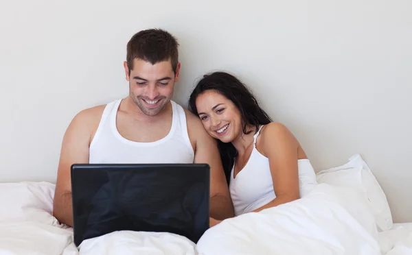 Яркая пара с ноутбуком на кровати — стоковое фото