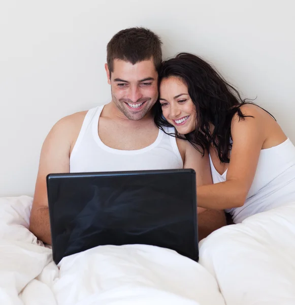 Lachen paar met behulp van een laptop in de slaapkamer — Stockfoto
