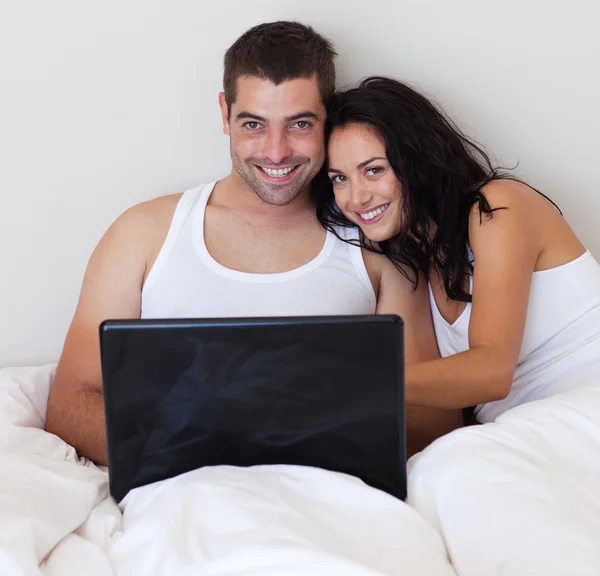 笑夫妇在卧室使用一台笔记本电脑 — 图库照片