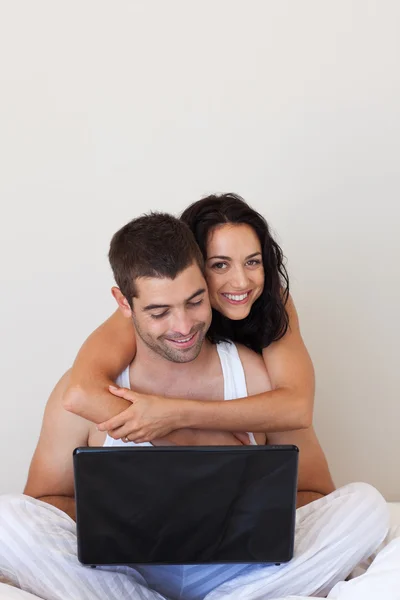 Bella coppia utilizzando un computer portatile seduto su un letto — Foto Stock