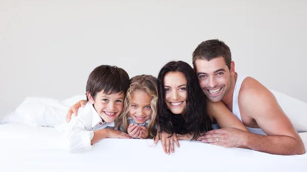 Família feliz deitada em sua cama — Fotografia de Stock