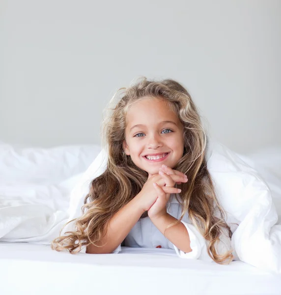 Portréja egy kedves aranyos lány feküdt egy ágyon — Stock Fotó