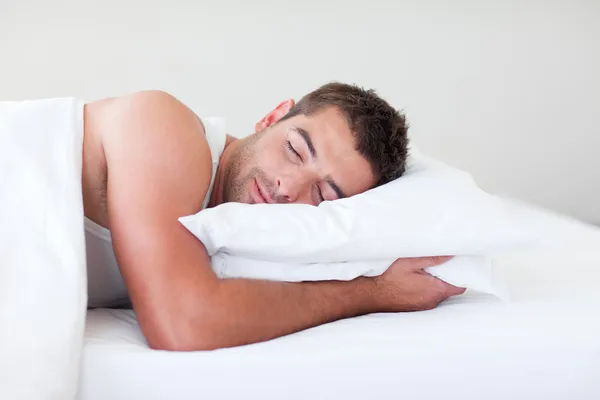 Bonito homem dormindo em uma cama — Fotografia de Stock