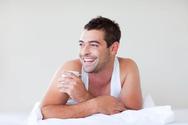 Άνθρωπος με ένα φλιτζάνι καφέ στο κρεβάτι — Φωτογραφία Αρχείου