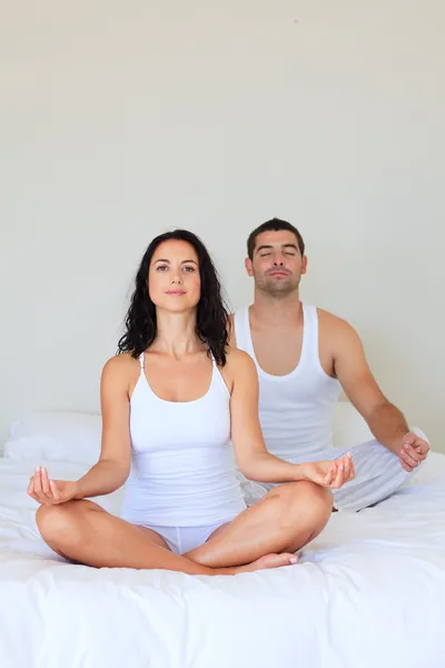 Par i meditation poserar på sängen — Stockfoto