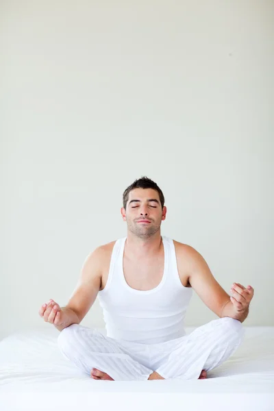 Человек, сидящий на кровати, медитируя — стоковое фото