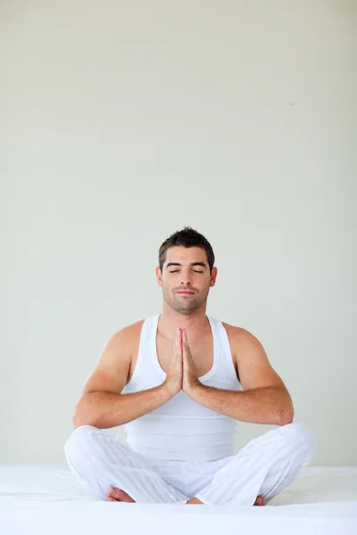 Young man doing yoga in bed with clossed eyes — Stock Photo, Image