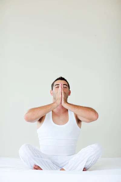 Young man doing yoga sitting in bed — Stock Photo, Image