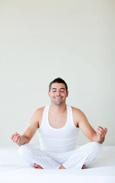 Usmívající se mladý muž dělá jógu v posteli — Stockfoto