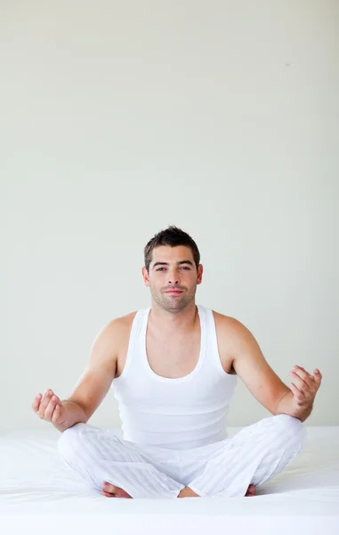 Young man doing exercises in bed — Stock Photo, Image