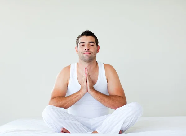 Jeune homme pratiquant le yoga au lit — Photo
