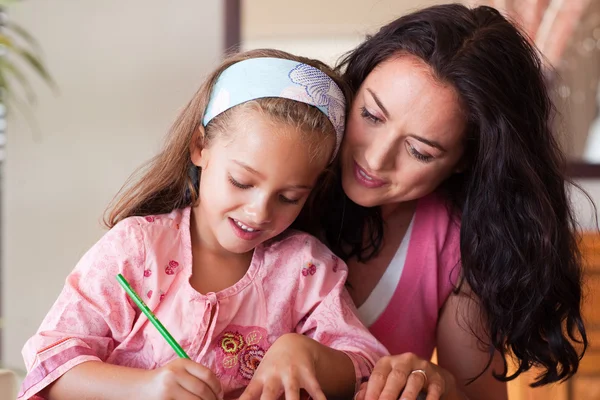 Gelukkig moeder haar dochter voor huiswerk te helpen — Stockfoto