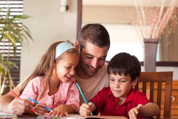 Padre sorridente che aiuta i suoi figli a fare i compiti — Foto Stock