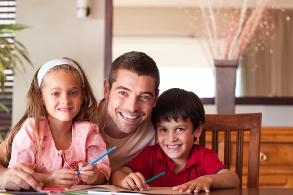 Sorrindo pai ajudando seus filhos para lição de casa — Fotografia de Stock