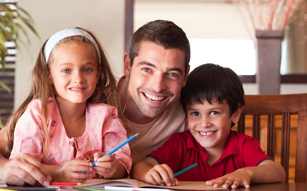 Glimlachend vader zijn kinderen voor huiswerk te helpen — Stockfoto
