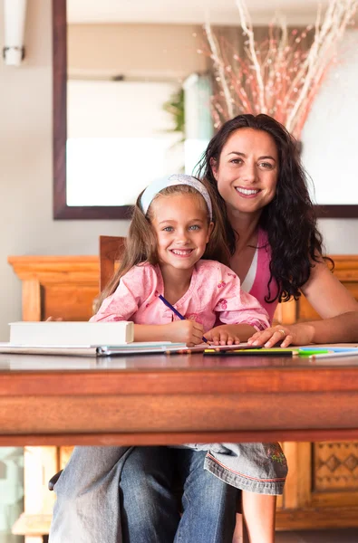 Fröhliche Mutter hilft ihrer Tochter bei den Hausaufgaben — Stockfoto