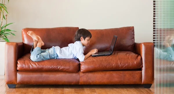 Kanepe üstünde a laptop ile oynayan çocuk — Stok fotoğraf