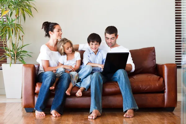 Familia feliz jugando juntos con un ordenador portátil —  Fotos de Stock