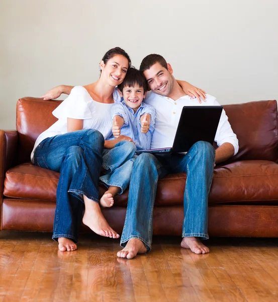 Mutlu bir aile başparmak ile bir dizüstü bilgisayar kullanarak — Stok fotoğraf