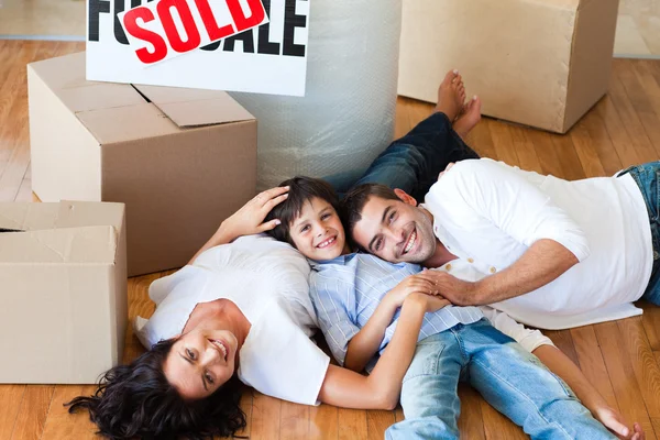 Lächelnde Familie in ihrem neuen Haus auf dem Boden liegend — Stockfoto