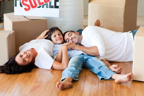 Família em uma nova casa deitada no chão com caixas — Fotografia de Stock