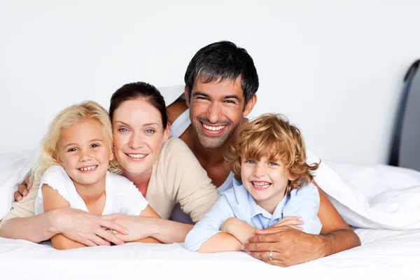 Smiling family together on bed — Stock Photo, Image