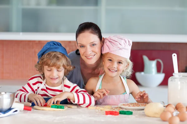 Fröhliche Mutter backt mit ihren Kindern — Stockfoto