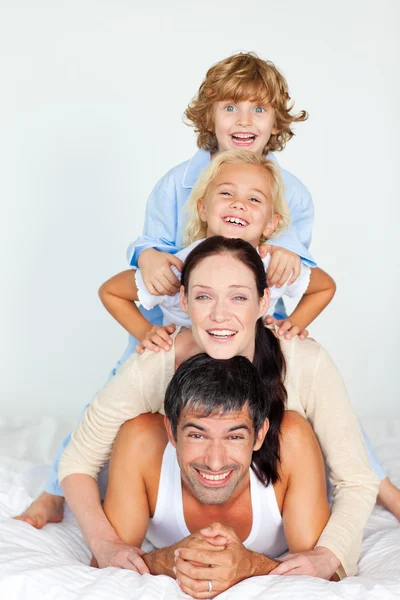 Веселая семья лежит на белой кровати — стоковое фото