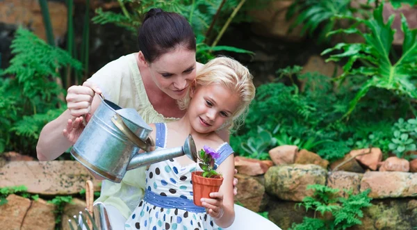 若い母親と娘の植物に水をまく — ストック写真