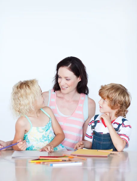 Mãe ajudando seus filhos fazendo lição de casa — Fotografia de Stock