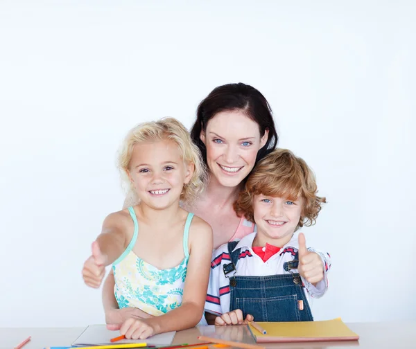 Crianças fazendo lição de casa com a mãe com os polegares para cima — Fotografia de Stock