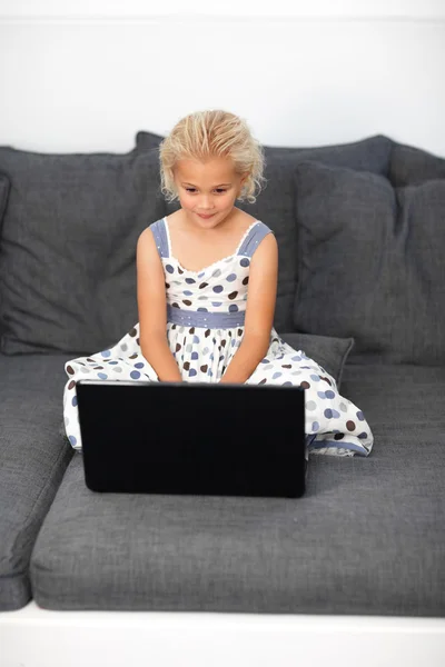 可爱的女孩在沙发上使用一台笔记本电脑 — 图库照片