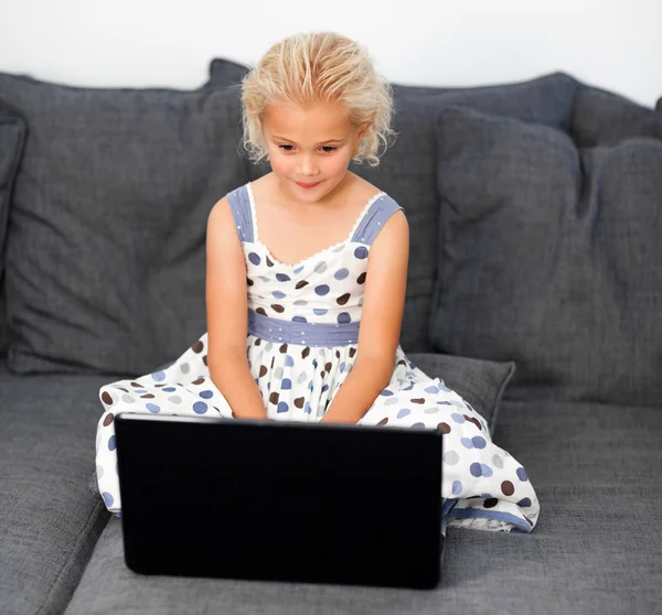 年轻的姑娘在沙发上使用一台笔记本电脑 — 图库照片