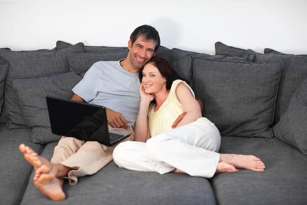 Couple radieux utilisant un ordinateur portable sur un canapé — Photo
